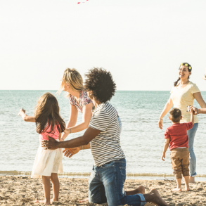children and adult on a beach flying a kite
