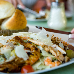 dining table with woman eating a shrimp salad