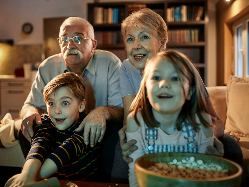 grandparents and grandchildren watching a movie and eating popcorn