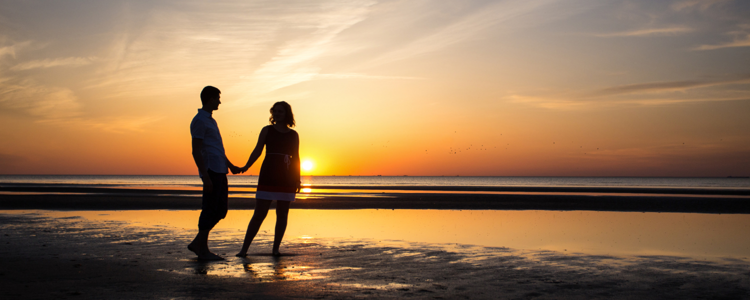 couple walking on beach at sunset