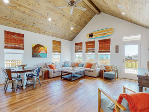 vacation rental living room and dining area with surf board on wall