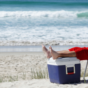 santa sitting on beach in chair with feet on a cooler