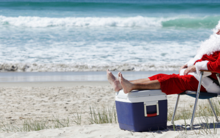 santa sitting on beach in chair with feet on a cooler