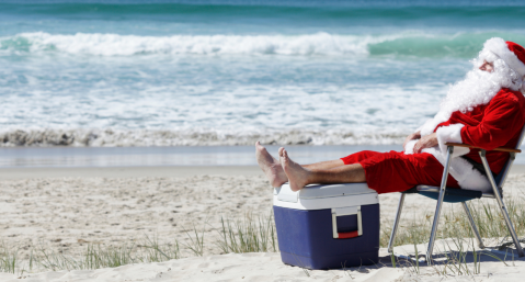 santa sitting on beach in chair with feet on a cooler