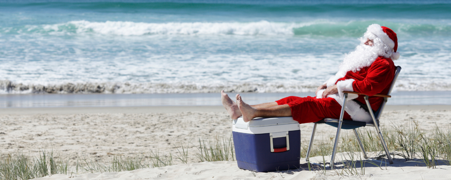 santa sitting on beach in chair with feet on a cooler
