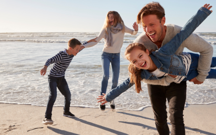 family of four in warm clothes playing on beach