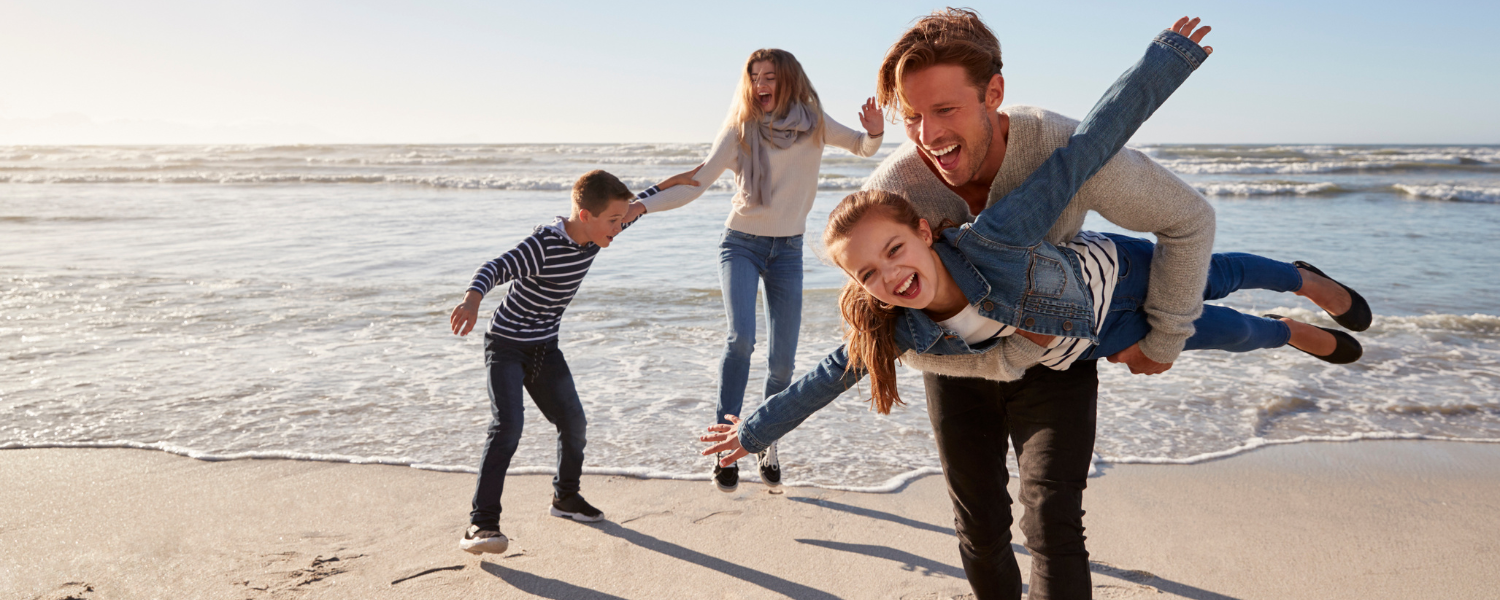 family of four in warm clothes playing on beach